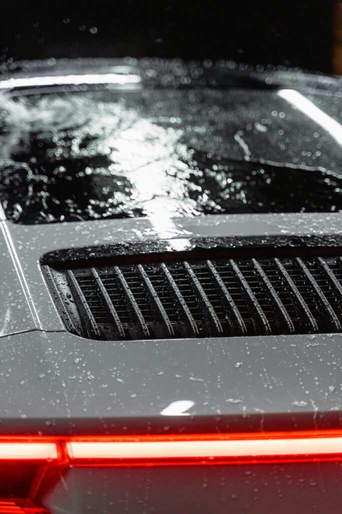 Close-up view of a luxury sports car with rain droplets on the surface, showcasing sleek design.
