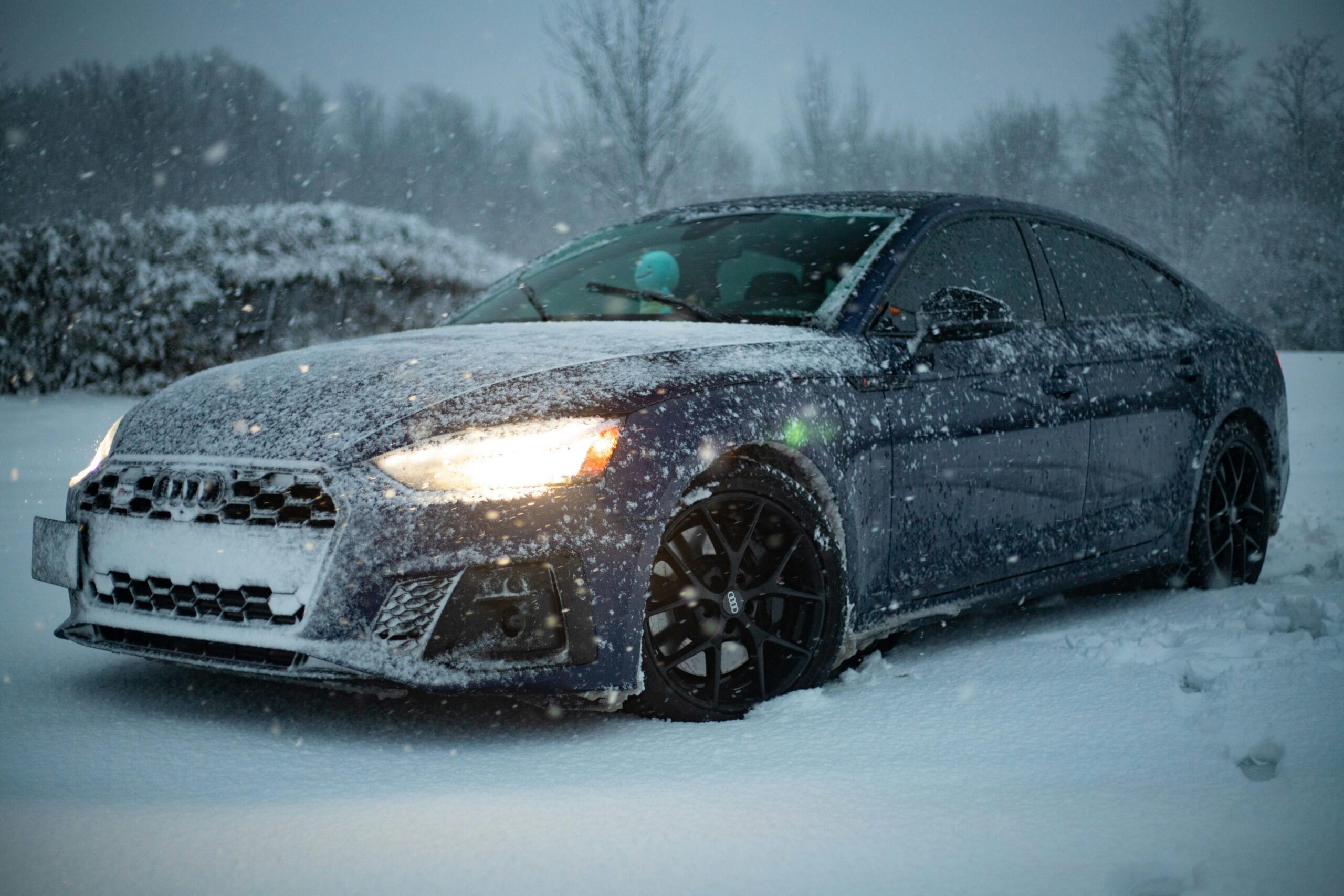 Luxury car covered in snow on a winter day, showcasing resilience and design.